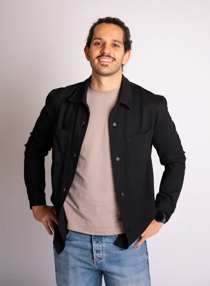 Filipe Simões, CEO e fundador do programa BMFIT e personal trainer online. Filipe está de pé, com um sorriso e mãos à cintura